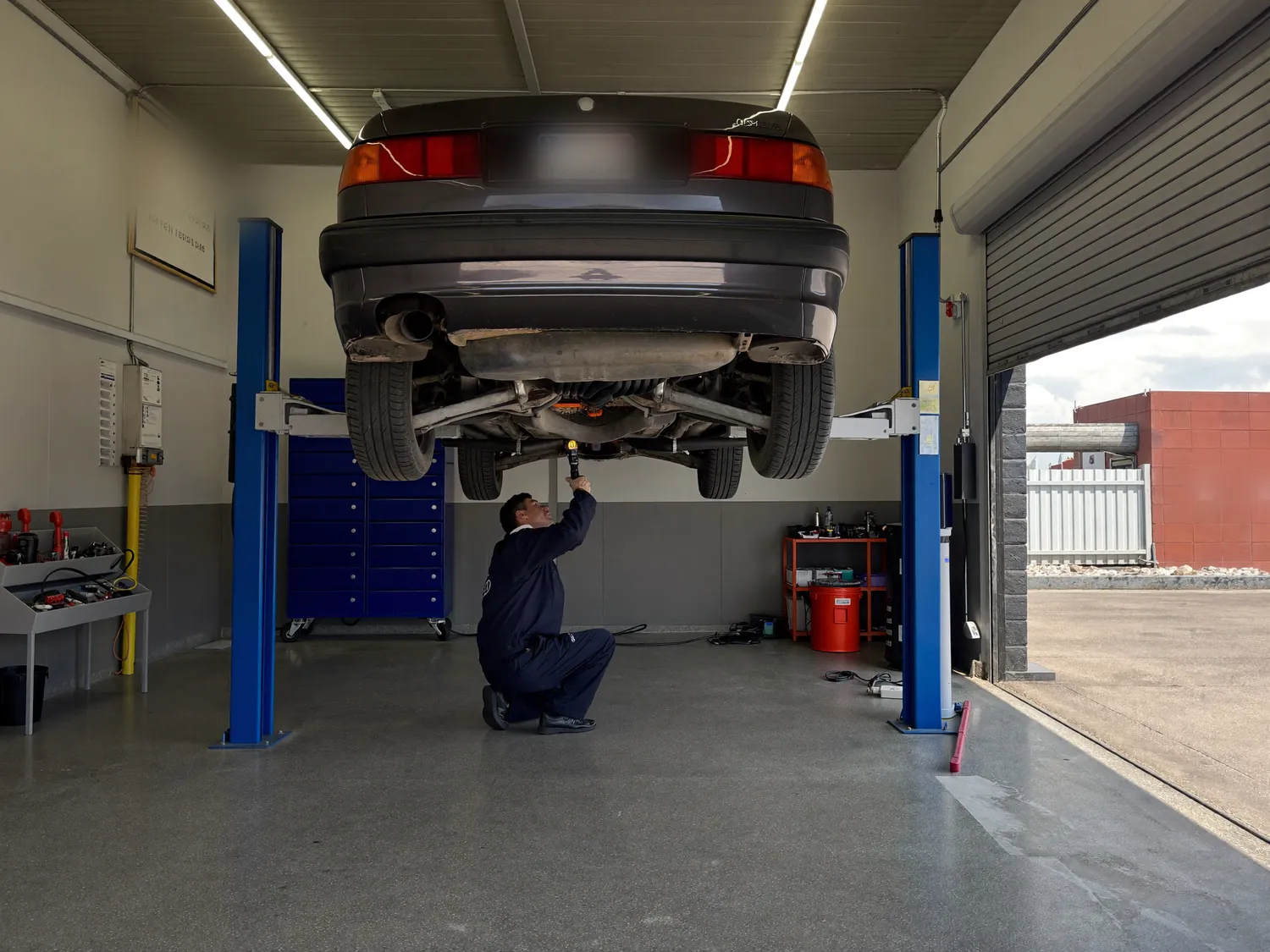 A car raised on a lift with a technician underneath