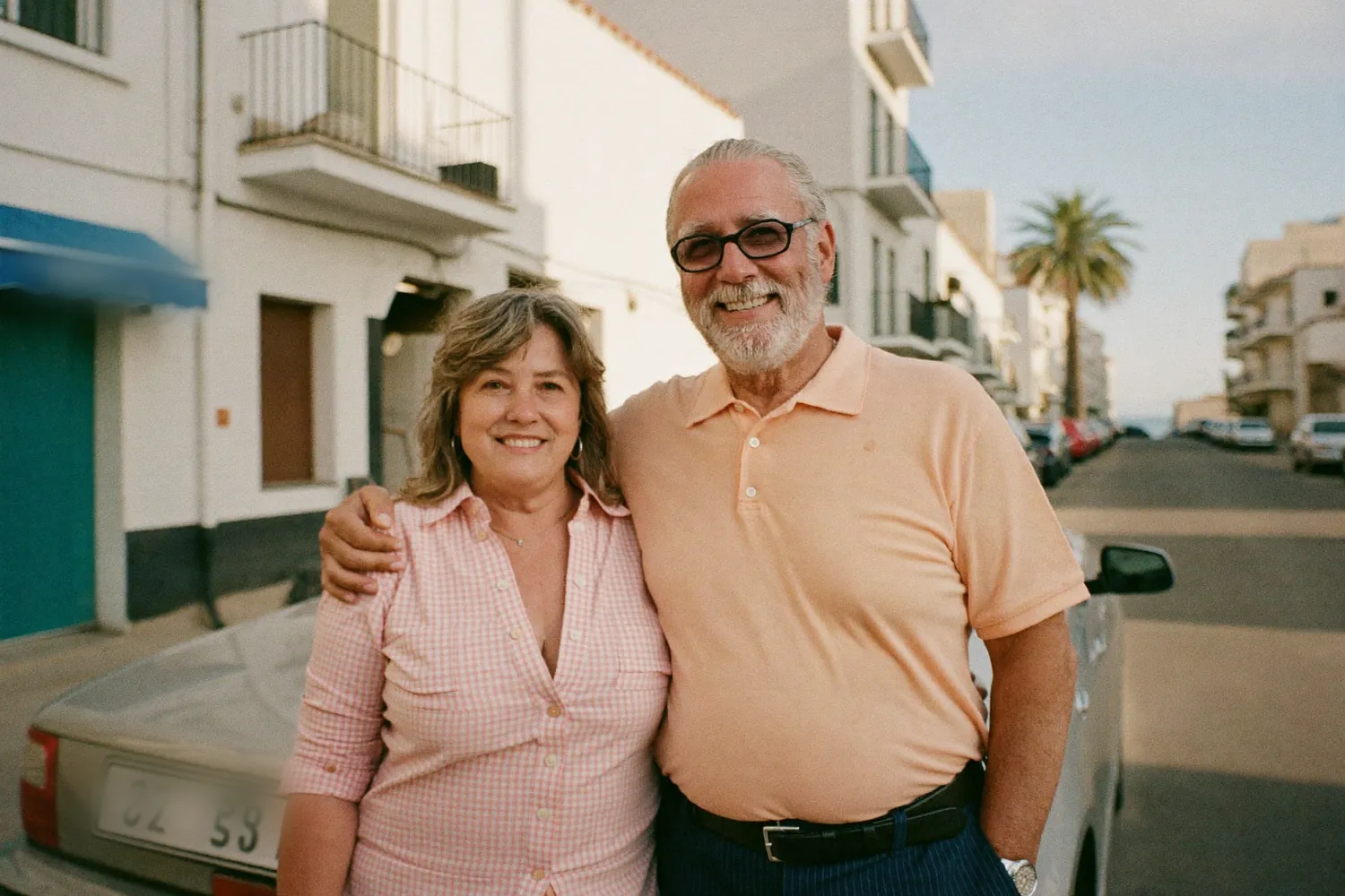 A couple standing beside their car on a coastal street