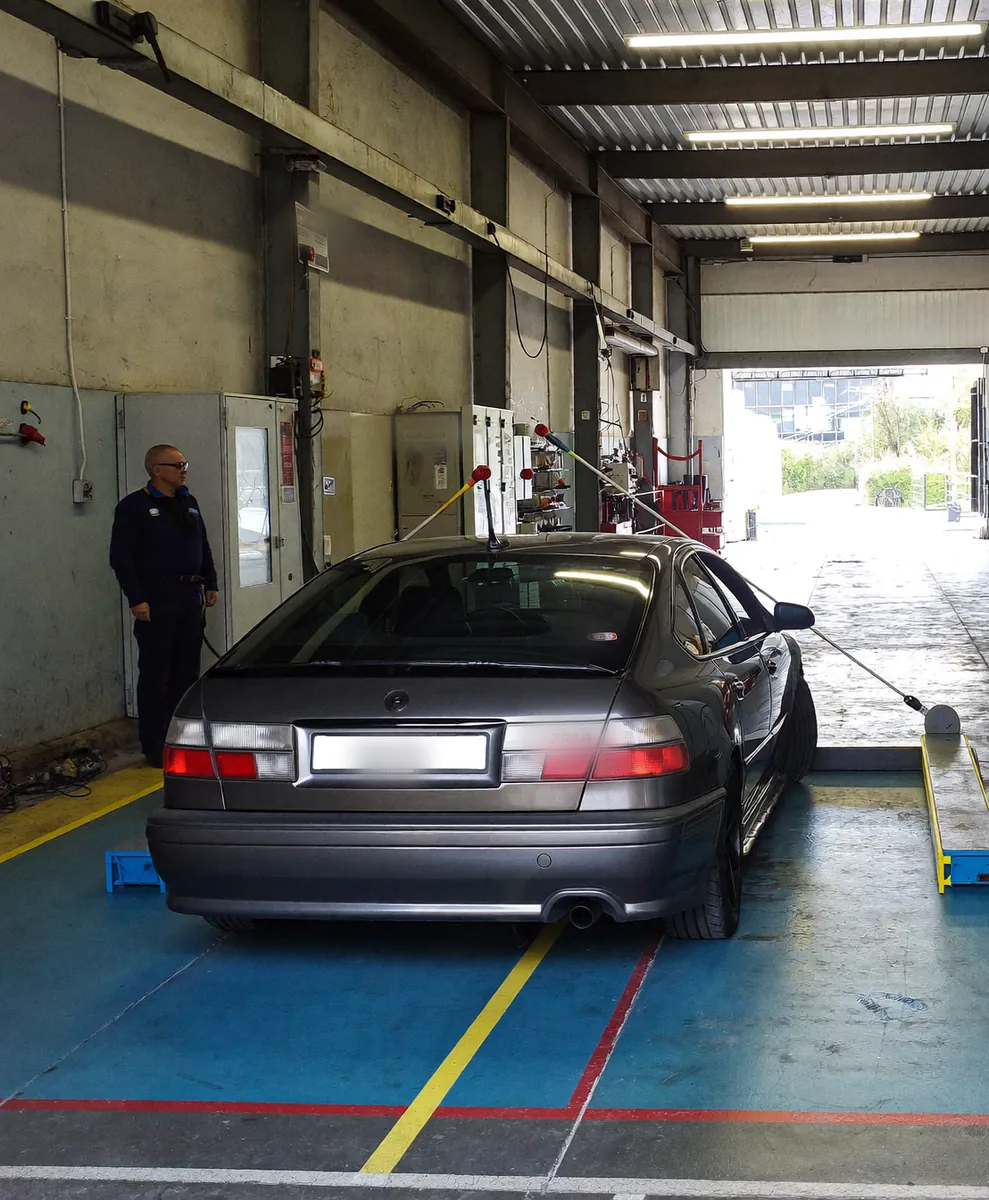 A car in a vehicle inspection lane with an inspector alongside