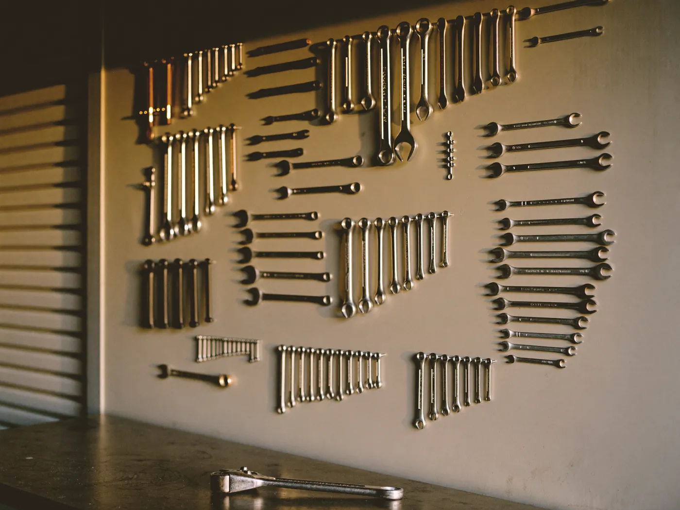 A tidy workshop tool wall with a torque wrench on the bench